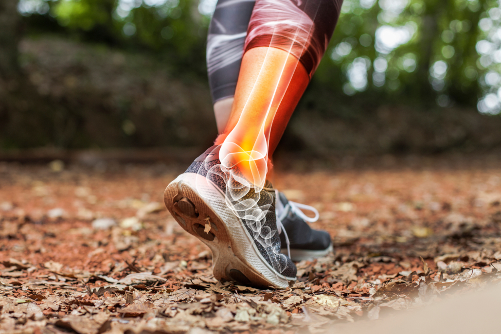 Person running on a leaf-covered trail wearing cleats.